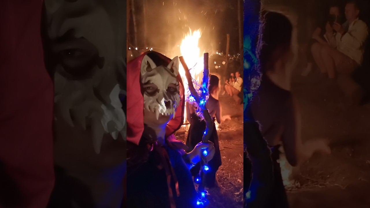 Witch dancing by the fire, in front of the demon. Fantasy festival. La sorĉistino dancas ĉe la fajro