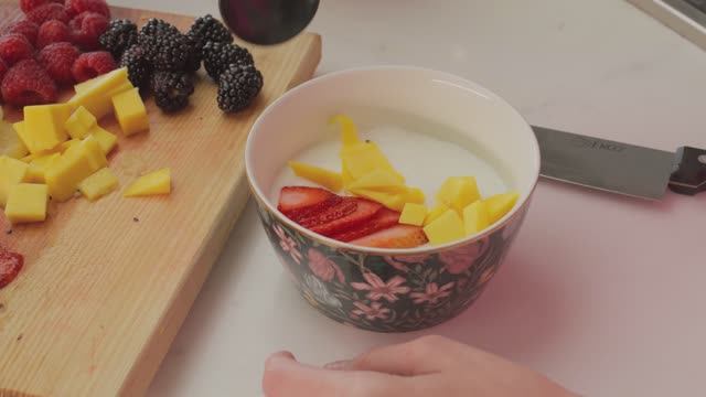 4K. Mixkit-preparing-a-bowl-with-yogurt-and-fruit.