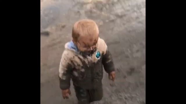 Маленький мальчик бегает по луже
