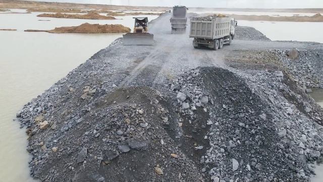 Строительство, дорога через озеро, обзор с другого дрона