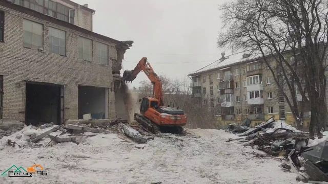 Работа экскаватора при демонтаже здания