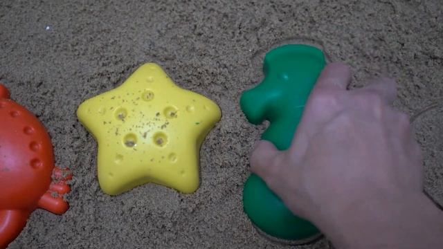 Ladybug made of sand plays in sandbox with beach toys listens to children's song