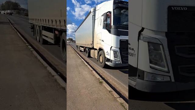 A truck drives along the road and picks up goods from a semi-trailer