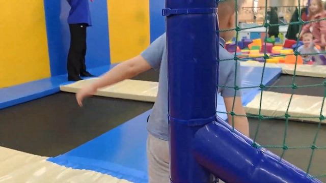 A child plays with trains on a playground, slides down a slide and runs through a maze