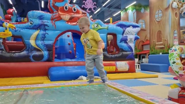 A child runs around the playground, plays catch and slides down the slide.