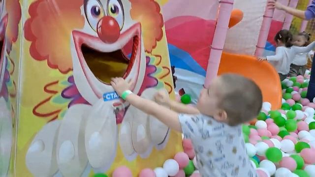 Playground child in colored balls rides down a slide