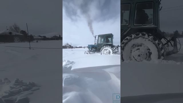 МТЗ едет по заснеженной дороге в метель