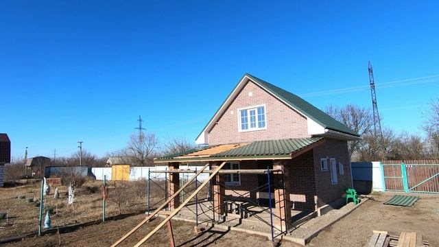 Парень монтирует металлочерепицу и завершает строительство односкатной крыши