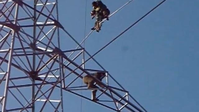 Two persons climb extra high voltage 220-kV electricity pylon