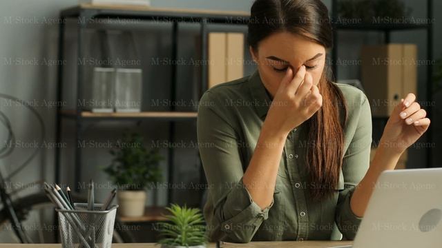 Exhausted young business woman taking off her glasses after long work with laptop computer in the