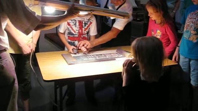 Paul Herrera demonstrating and showing young folks how to cut letters in stone.