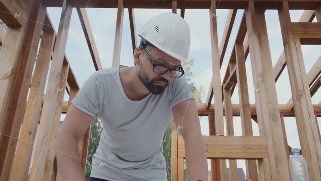 Engineer in a helmet works against the background of scaffolding.