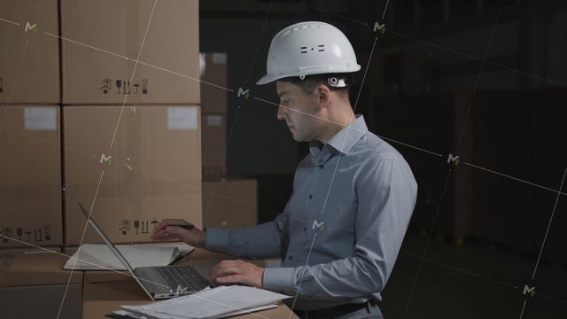 Man in a warehouse works with laptop on background of cardboard boxes
