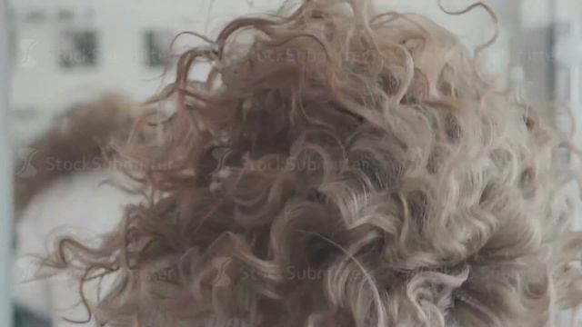 A young woman after a hairdresser admires a new hairdo
