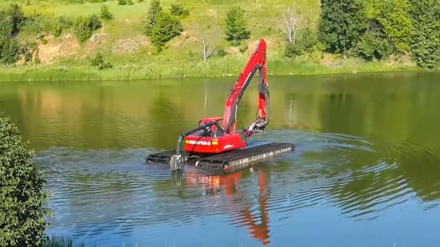 Понтонный экскаватор, оснащенный землесосом  плывет по воде