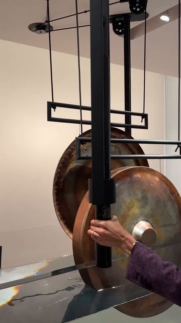 Visitor striking a gong over water in the new Mandala Lab at the Rubin Museum of Art, New York