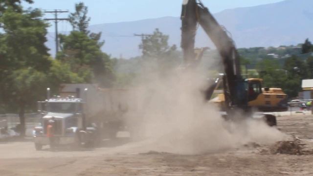 Volvo EC460C Excavator loading a big rig dump truck with asphalt from a demolished parking lot.