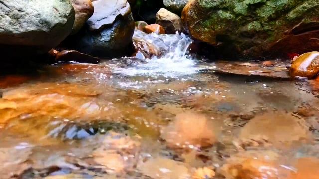Шумный разлив воды между камней. Пейзажный вид на ручей. Умиротворение на видео.