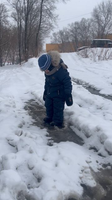 Володя ходит по лужам среди снега