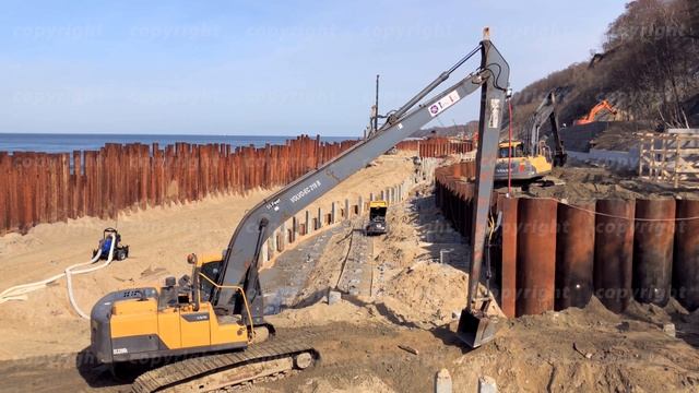 Excavator works on the seashore, strengthening the Baltic Sea coastline