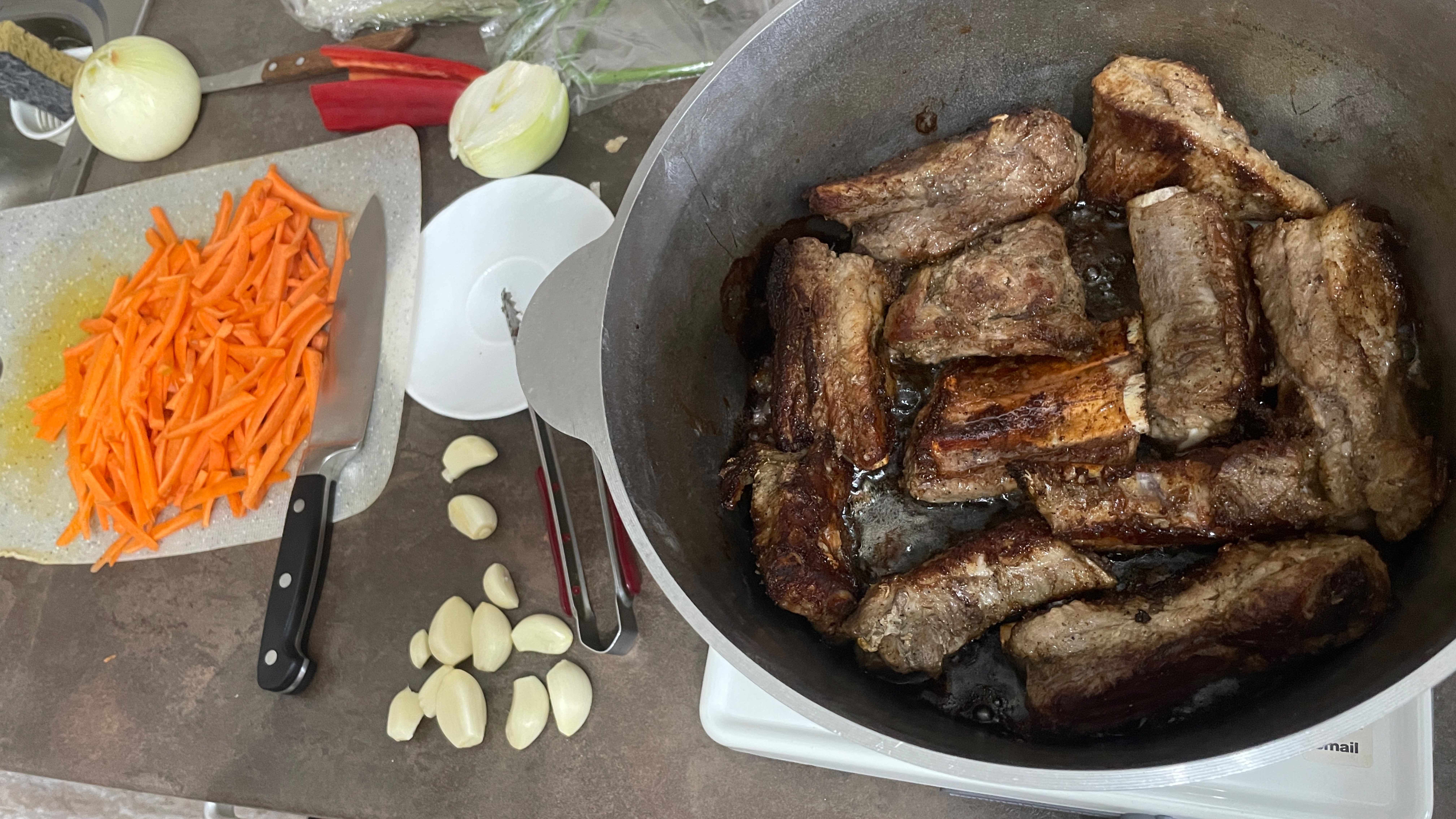 Ребра с овощами и картошкой в казане на электроплитке.