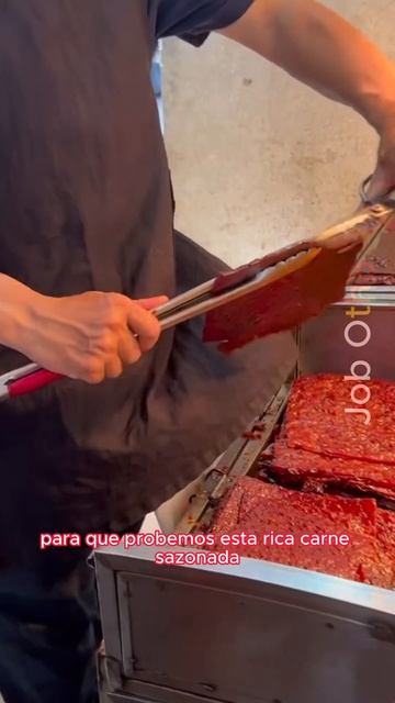 Vendedor ofreciendo muestras de carne gratuitas en un puesto callejero del Dongmen rd.