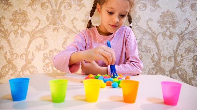 София играет и сортирует шарики по стаканчикам и учит цвета по английски