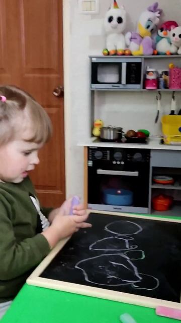 Ребенок рисует цветными мелками на доске.