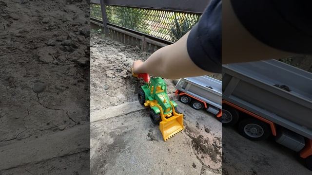 Мальчик играет с трактором и самосвалом
