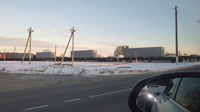 Поезд - контейнеровоз едет через переезд. Ясное зимнее