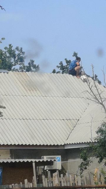 Вдалеке человек ремонтирует крышу.