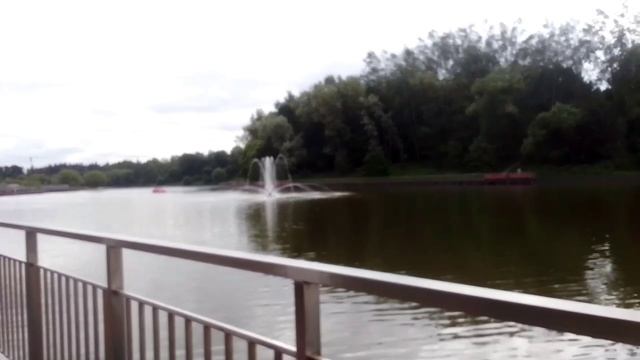 Розовая машина катамаран плывет по водоему у фонтана