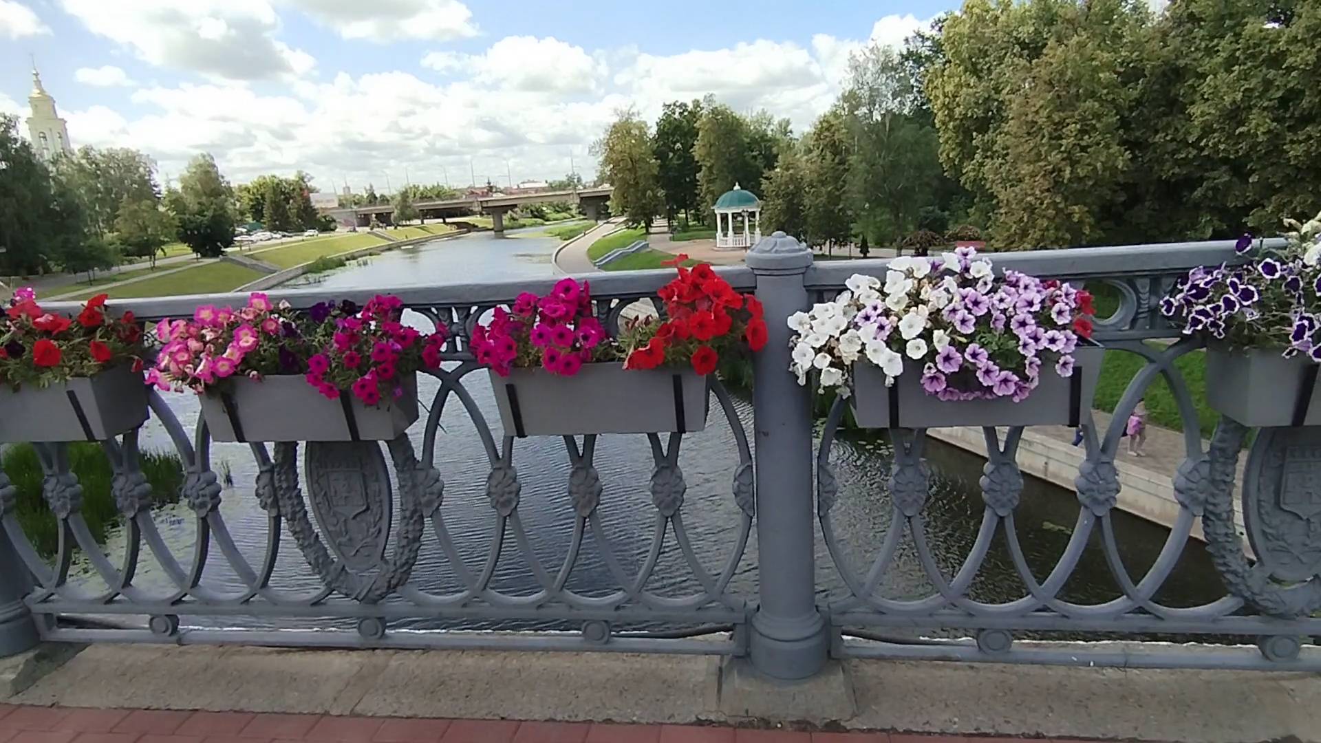 На мосту в подвесных ящиках цветут цветы петунии