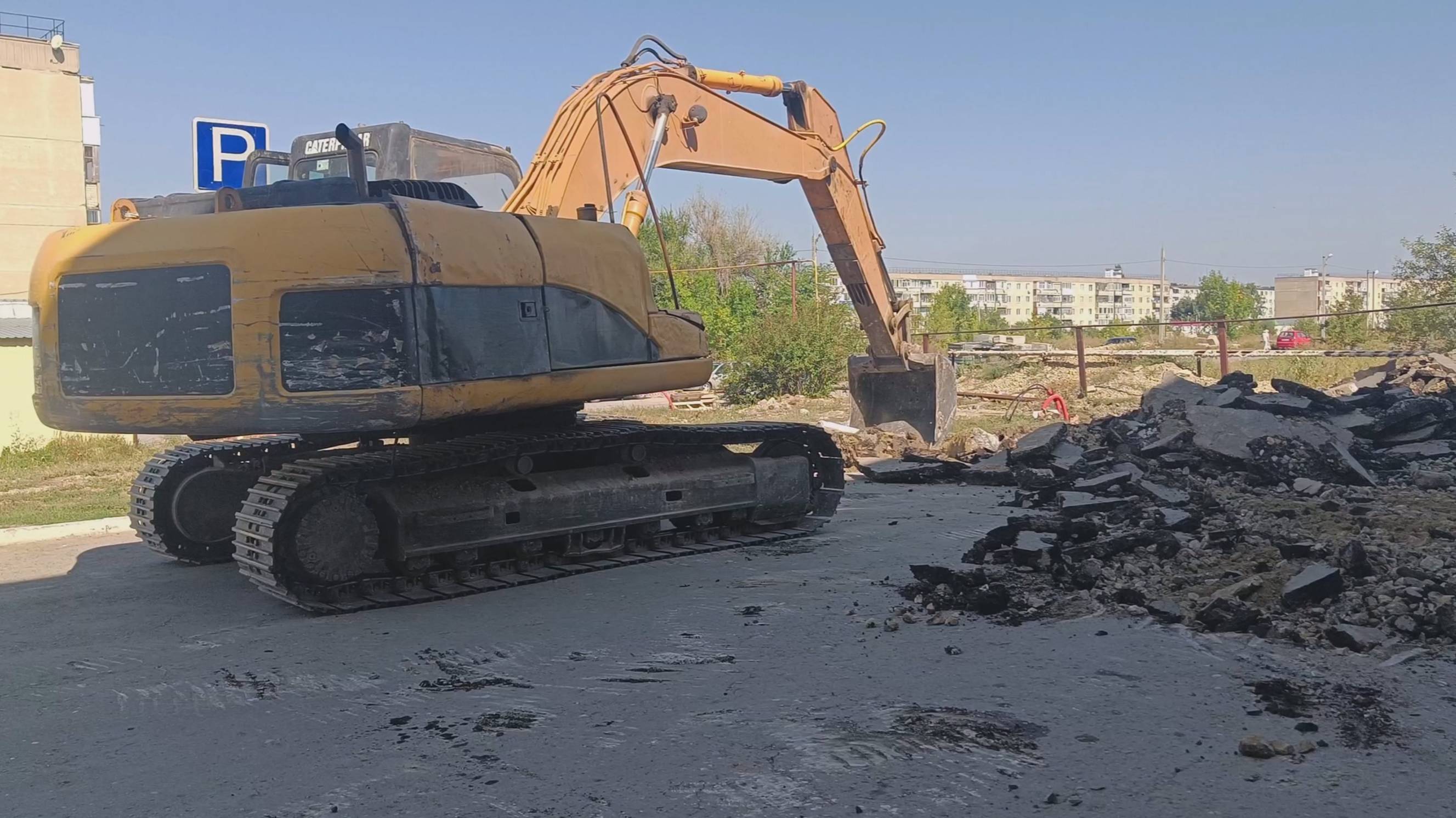 Экскаватор снимает асфальт