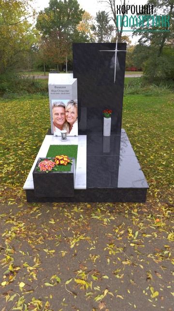 Женский памятник на могилу с металлической оградой по периметру участка с гранитными вазами