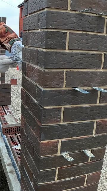 Работа каменщиков: процесс строительства кирпичного забора.