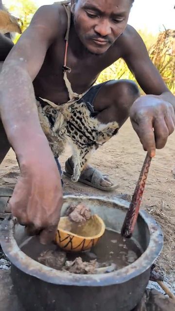 Охотник племени дегустирует сочный кусочек мяса и наваристый бульон