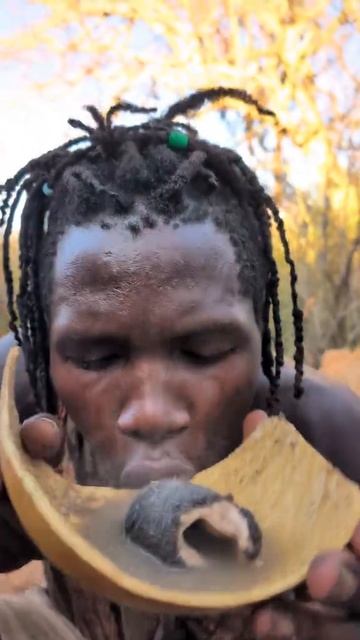 Житель племени пробует суп на костре, с кусочками потрохов