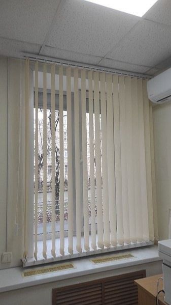 Нежные абрикосовые вертикальные жалюзи для оформления оконных проемов в офисном помещении.