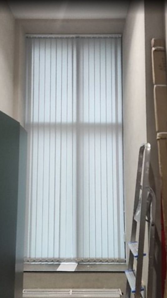 Стильные серые вертикальные жалюзи на большое окно в подсобное помещение для персонала. Декор.