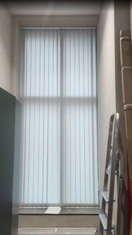 Стильные серые вертикальные жалюзи на большое окно в подсобное помещение для персонала. Декор.