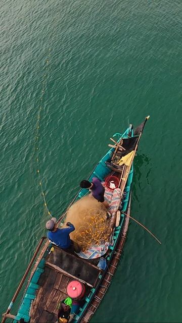 Одинокий вьетнамский рыбак вытягивает сеть на рассвете в бухте Ланг-Ко