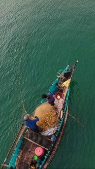 Одинокий вьетнамский рыбак вытягивает сеть на рассвете в бухте Ланг-Ко