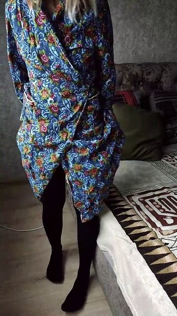 Женщина одевает колготки на свои ножки в домашнем халате