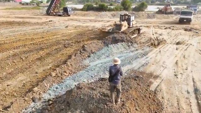 Хороший оператор-погрузчик, перемещающий грунт по текущей воде и строящий временную дорогу