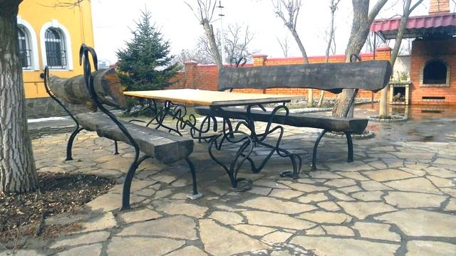 Красивый стол и скамейки из бревен во дворе дома