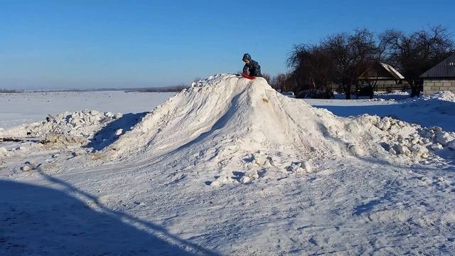 Тёма катается с горки на ледянке.