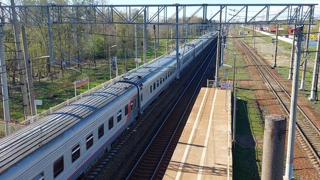 Пассажирский поезд с локомотивом ЭП20 - 018 пролетает платформу Металлострой в Санкт-Петербурге