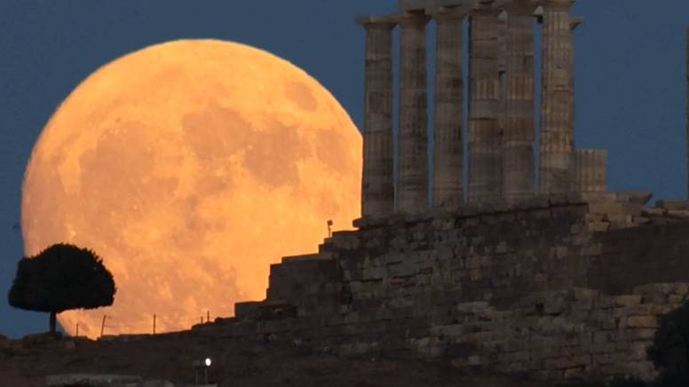 Суперлуние в ночном небе над храмом Посейдона в Афинах