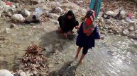 Displaced and homeless: Displaced woman going to the river bank to wash blankets and clothes